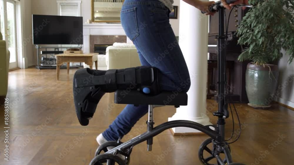 Woman using a knee scooter in a house