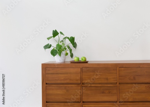 Plant with green apples on wood cabinet