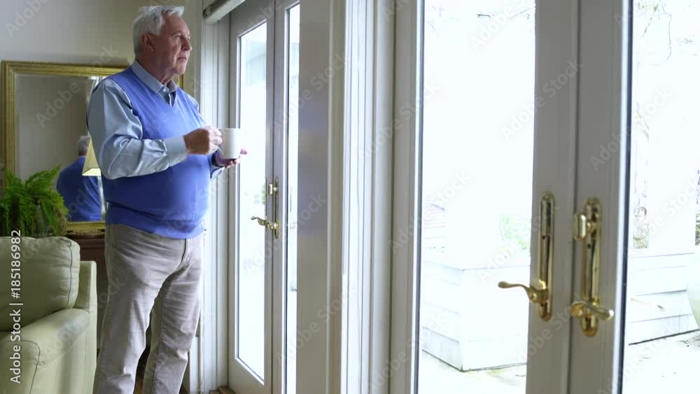 Senior man drinking coffee and looking out of patio door Senior man drinking coffee and looking out of patio door