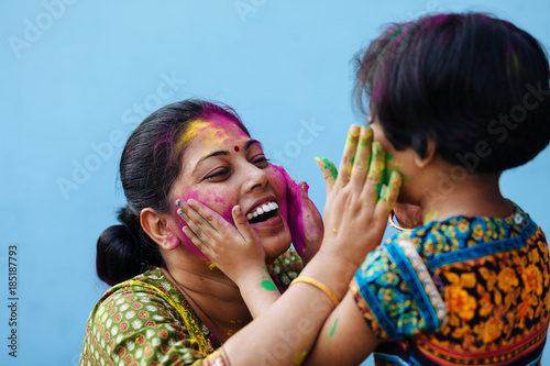 Little girl playing holi with her mother with color powder photo