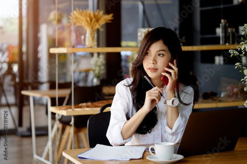 Portrait of an attractive young woman holding her phone while working in coffee shop.