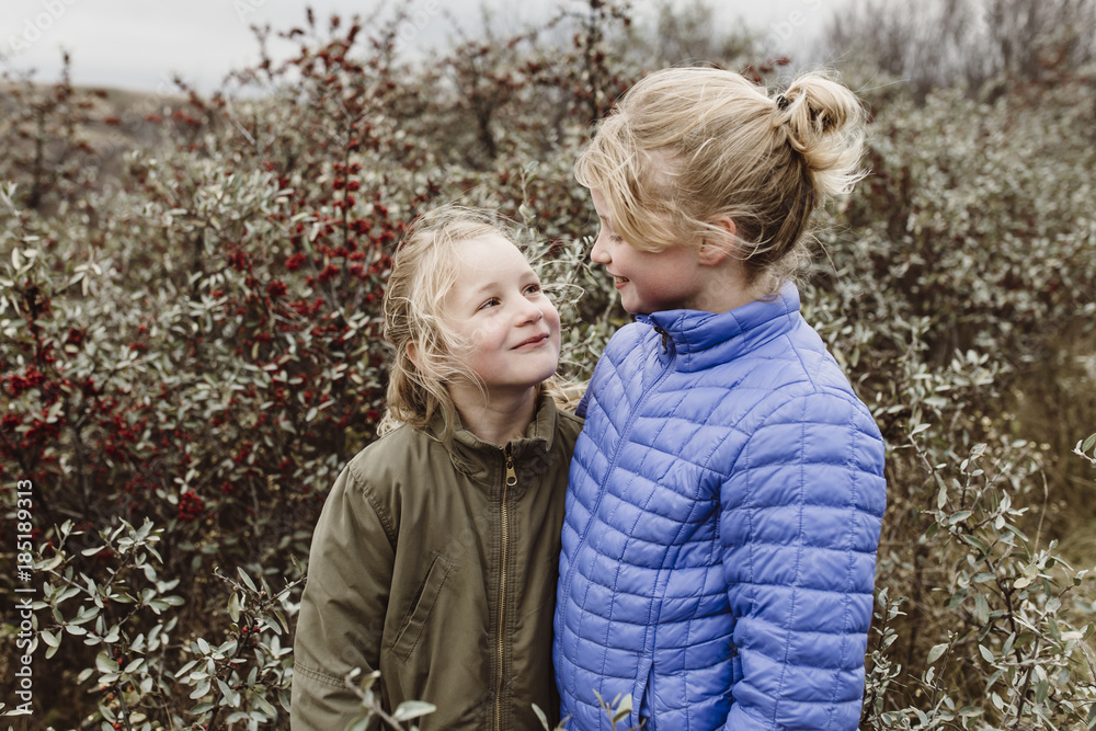 Outdoor portrait of young sisters in field of berries Outdoor portrait of young sisters in field of berries