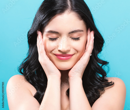 Beautiful young woman touching her face in skin care theme