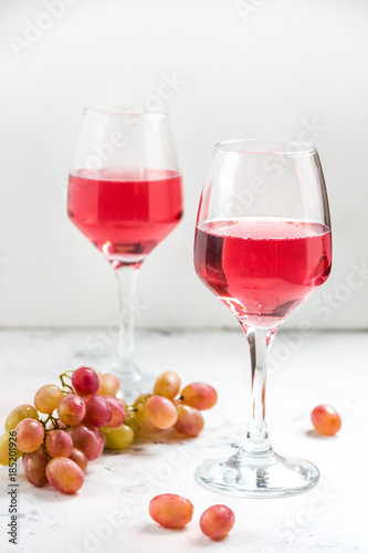 Pink wine and a grape on the white background