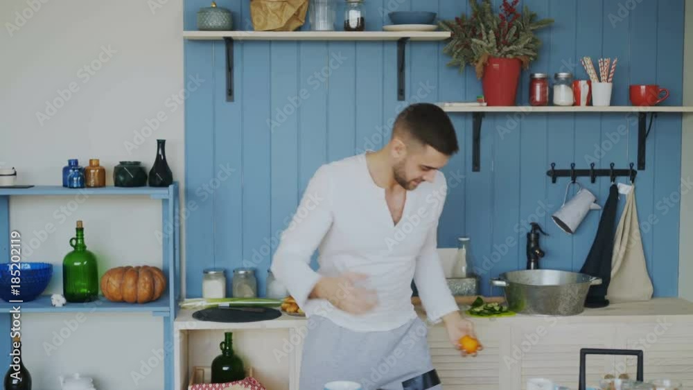 Funny cheerful man juggle with orange mandarins it the kitchen at home Funny cheerful man juggle with orange mandarins it the kitchen at home