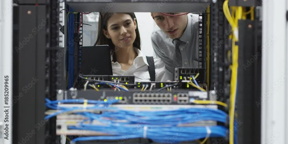 Team of people working in a data centre with rows of server racks and ...