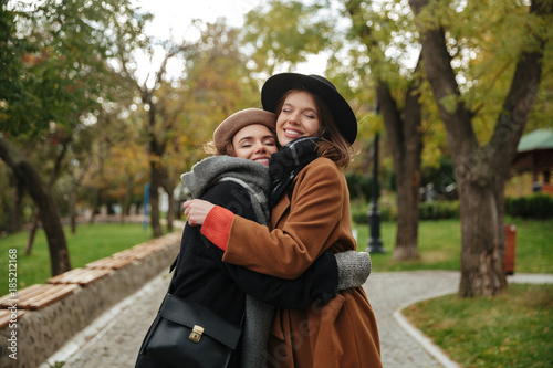 Portrait of two smiling girls dressed in autumn clothes hugging