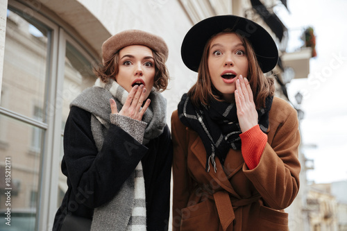Portrait of two surprised girls dressed in autumn clothes