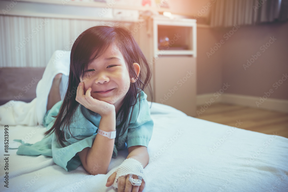 Illness asian child admitted in hospital with saline iv drip on hand.