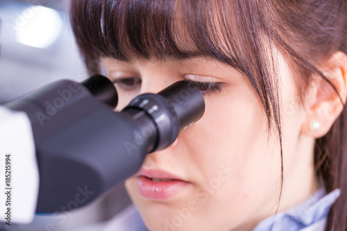 Doctor woman working a microscope. Female scientist looking through a microscope in lab. Student girl looking in a microscope, science laboratory concept