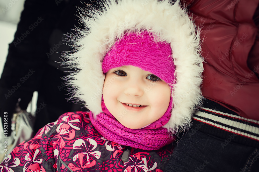 parents with little daughter in pink pattern coat smiling, hugging and spending time outdoors in the winter park. Concept of happy family parents with little daughter in pink pattern coat smiling, hugging and spending time outdoors in the winter park. Concept of happy family