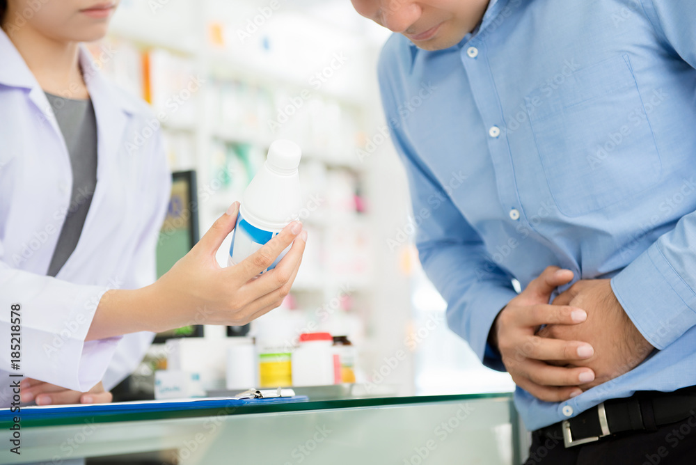 Male patient having stomach pain, consulting with pharmacist in drugstore