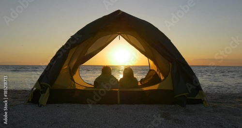 Romantic couple on the beach in the tent watching the sunrise