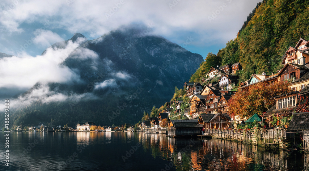 Scenic view of famous Hallstatt lakeside town reflecting in Hallstattersee lake in the Austrian Alps in morning light in autumn with clouds, Salzkammergut region, Austria