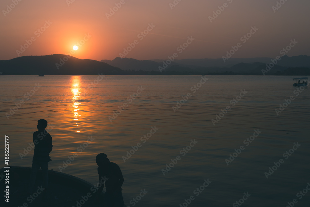 People Silhouette at sunset in backlight, river lake front, stunning landscape. Toned image.