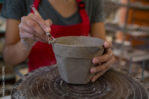 Female potter molding a mug with hand tool