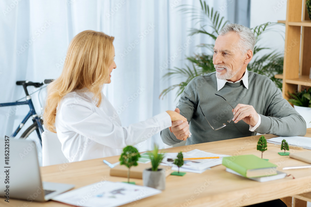 Deal. Smart qualified engineer feeling glad while sitting in her nice office and shaking hands with the new generous rich partner Deal. Smart qualified engineer feeling glad while sitting in her nice office and shaking hands with the new generous rich partner