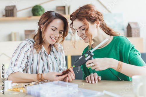young women making accessory with glue gun
