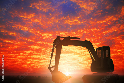 The silhouette of backhoe did excavation at construction site on sunset background.