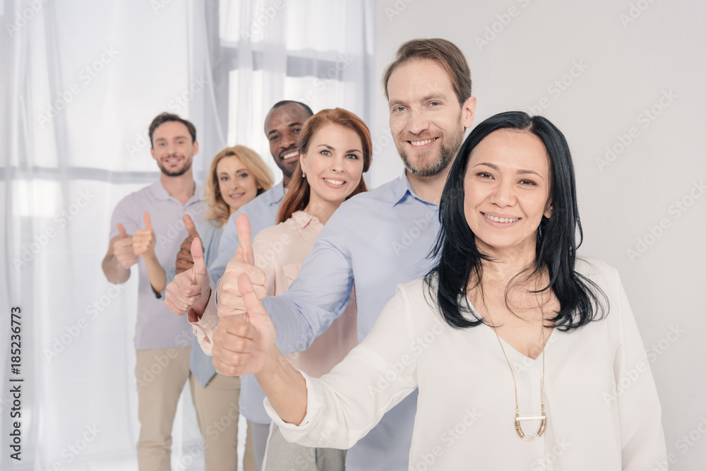 middle aged people smiling at camera and showing thumbs up during group therapy middle aged people smiling at camera and showing thumbs up during group therapy