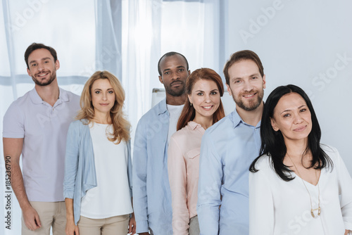 multiethnic mid adult people standing together and looking at camera