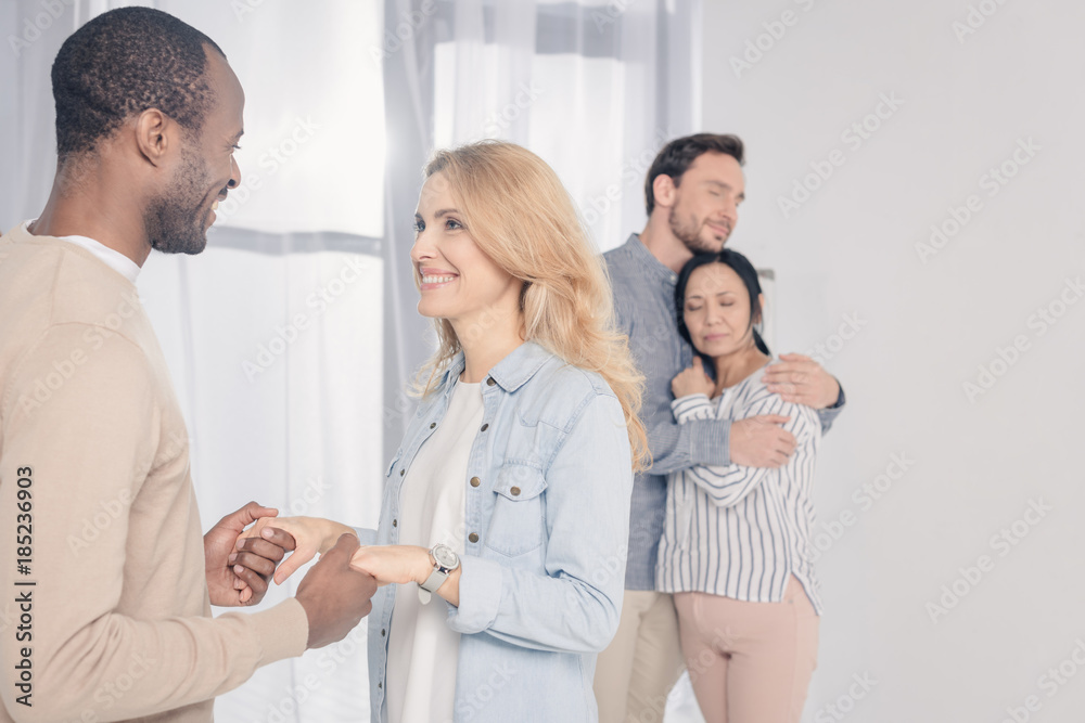 Obraz premium middle aged couples hugging and holding hands while supporting each other