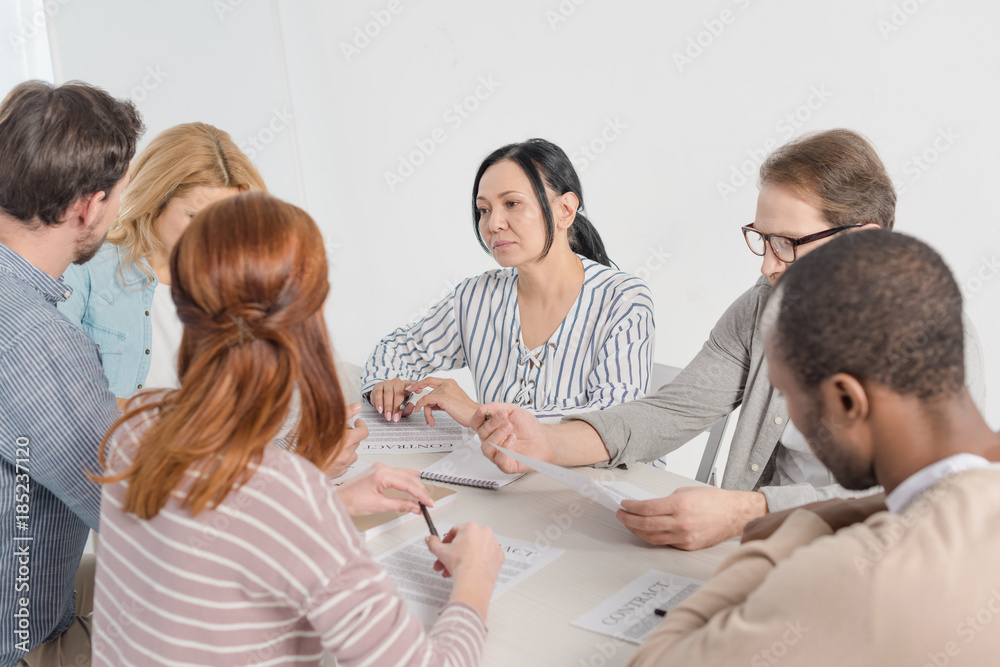 multiethnic group of people working together with papers multiethnic group of people working together with papers