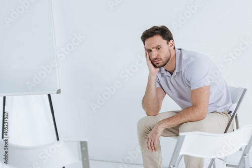 depressed man sitting and looking away in empty room