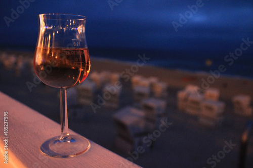 Rosé Weinglas auf Brüstung in der Abenddämmerung mit Strand und Meer verschwommen im Hintergrund.Where: Westerland, Sylt.When: 20.07.2013. photo