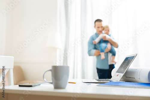 Dear person. Emotional sensible father feeling special connection between him and his little baby while holding this important little person in his arms