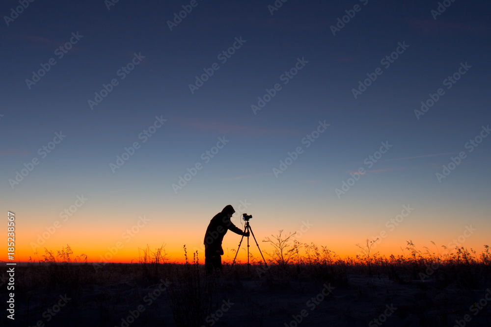 Sunrise: silhouette of photographer on work