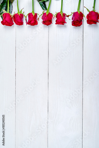 Top view of red roses border on white wooden background, copy space. Greeting card mockup for Saint Valentines Day, Womans Day (March 8), Mothers Day, flat lay. Love, wedding concept, free space