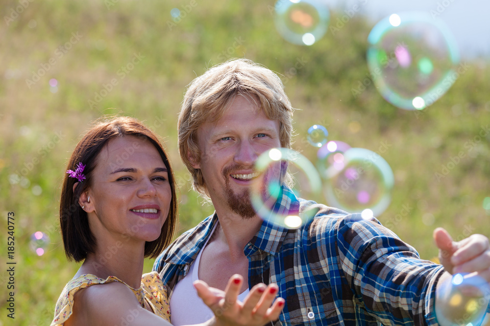 Happy smiling couple in love playing with soap bubbles Happy smiling couple in love playing with soap bubbles