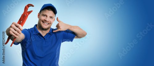 plumbing services - plumber with wrench showing phone call gesture on blue background with copy space