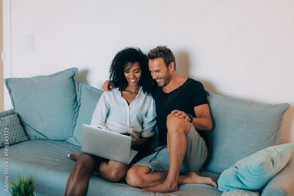 Happy young couple relaxed at home sitting in the couch on the computer Happy young couple relaxed at home sitting in the couch on the computer