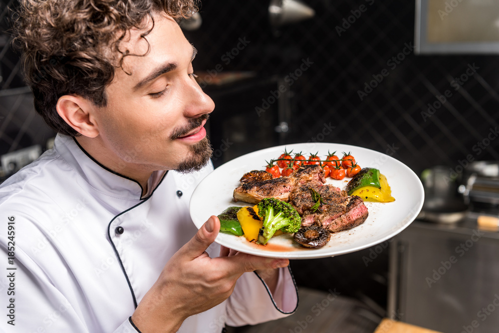 handsome chef sniffing smell of cooked dish