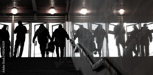 Human silhouettes against the bright doors. Exit from underground. People shadows with reflection on the wall