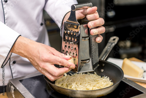 cropped image of chef grating cheese on grater photo