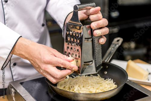 cropped image of chef grating cheese on grater