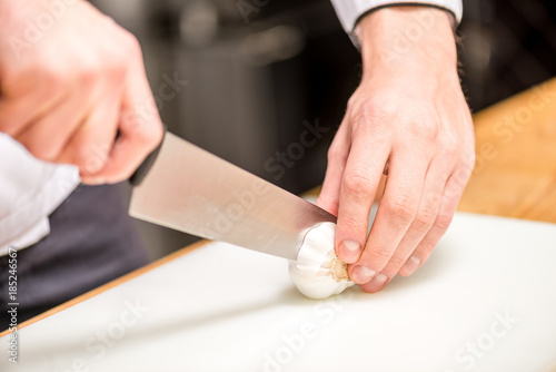 cropped image of chef cutting garlic