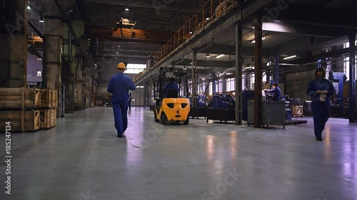 Industrial workers working on metallurgical plant and driving forklift truck