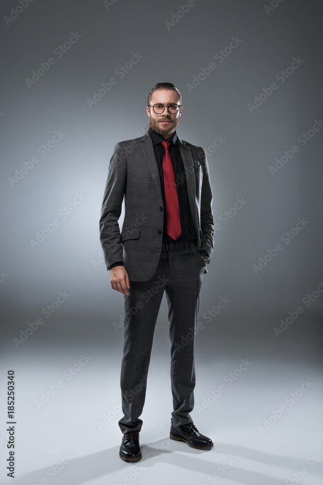 Seruous businessman in glasses in formal suit looking at camera, isolated on gray Seruous businessman in glasses in formal suit looking at camera, isolated on gray