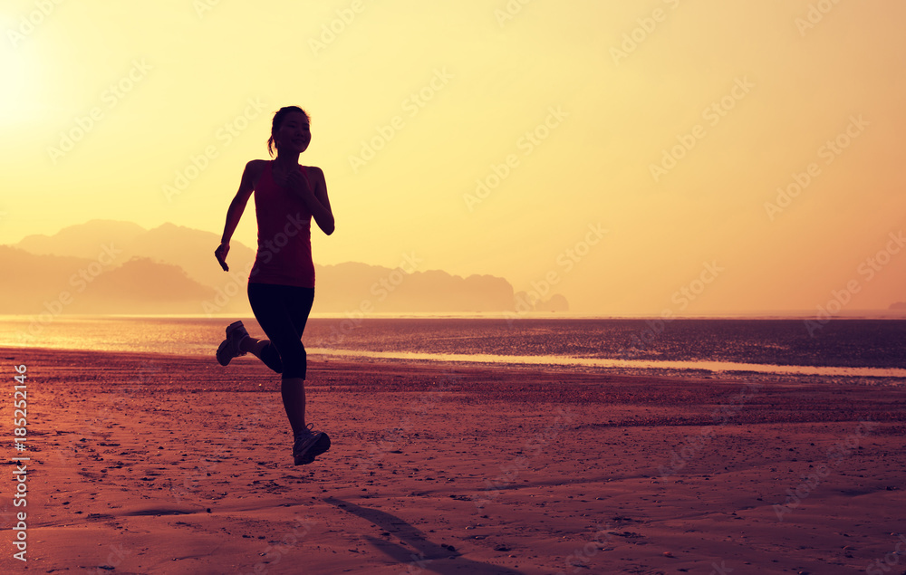 Young fitness woman running on sunrise sandy beach