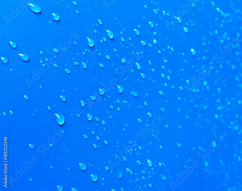 Close up view. Water droplets are stick on the blue wall surface.