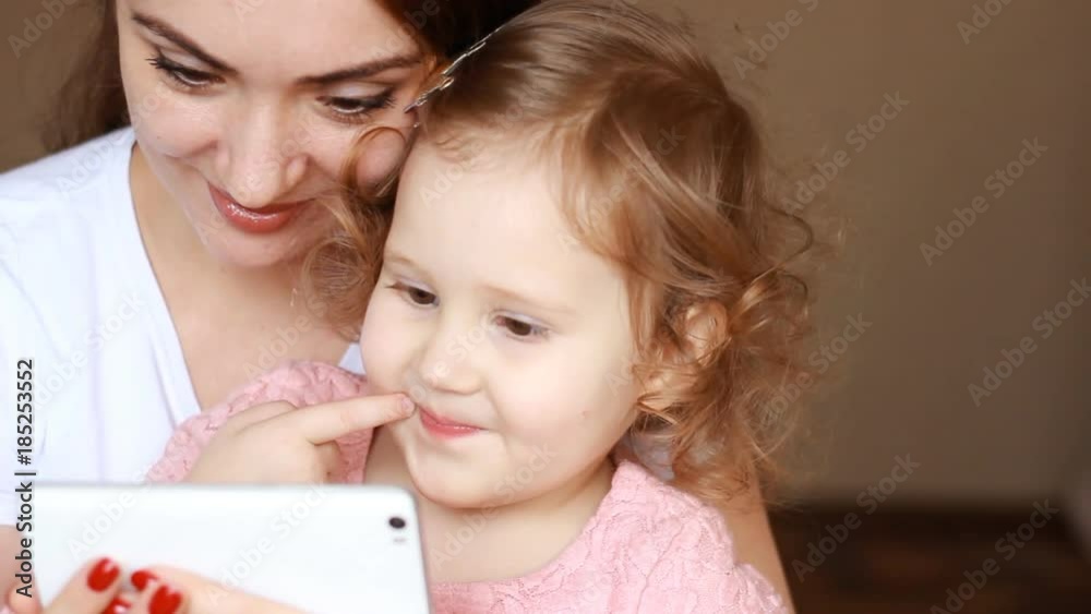 Mother and child looks at the phone screen and plays downloaded application on a smart phone close-up. Mom and her little daughter looking cartoon and playing the game. Close-up. Mother and child looks at the phone screen and plays downloaded application on a smart phone close-up. Mom and her little daughter looking cartoon and playing the game. Close-up.