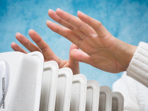 Female hands above the heater photo