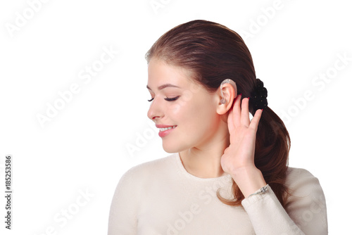 Cute girl with hearing aid looks aside and smile. At isolated white background.