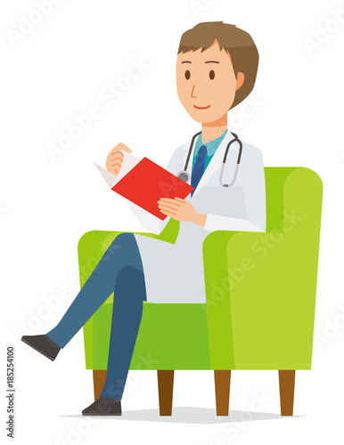 A young male doctor wearing a white suit sits on a sofa and is reading books