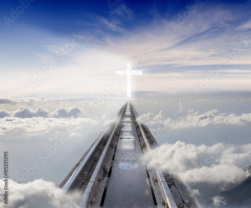 Fotografie railway tracks leading among the clouds to the glowing cross
