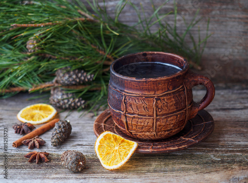 large coffee mug, pine branch with pine cones,dried oranges on a wooden table © androsov858